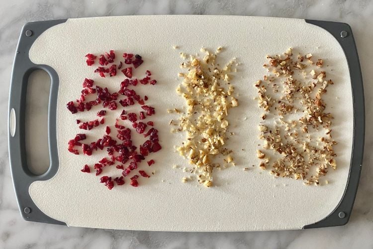 Chopped cranberries pecans and walnuts on cutting board