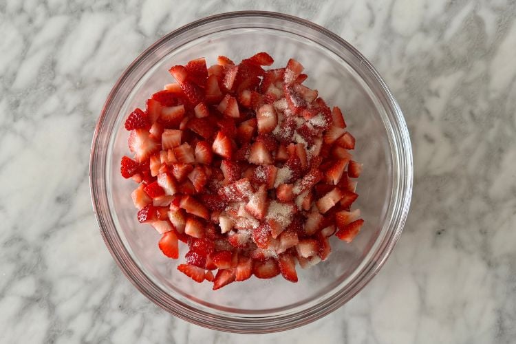 Chopped strawberries in bowl with sugar