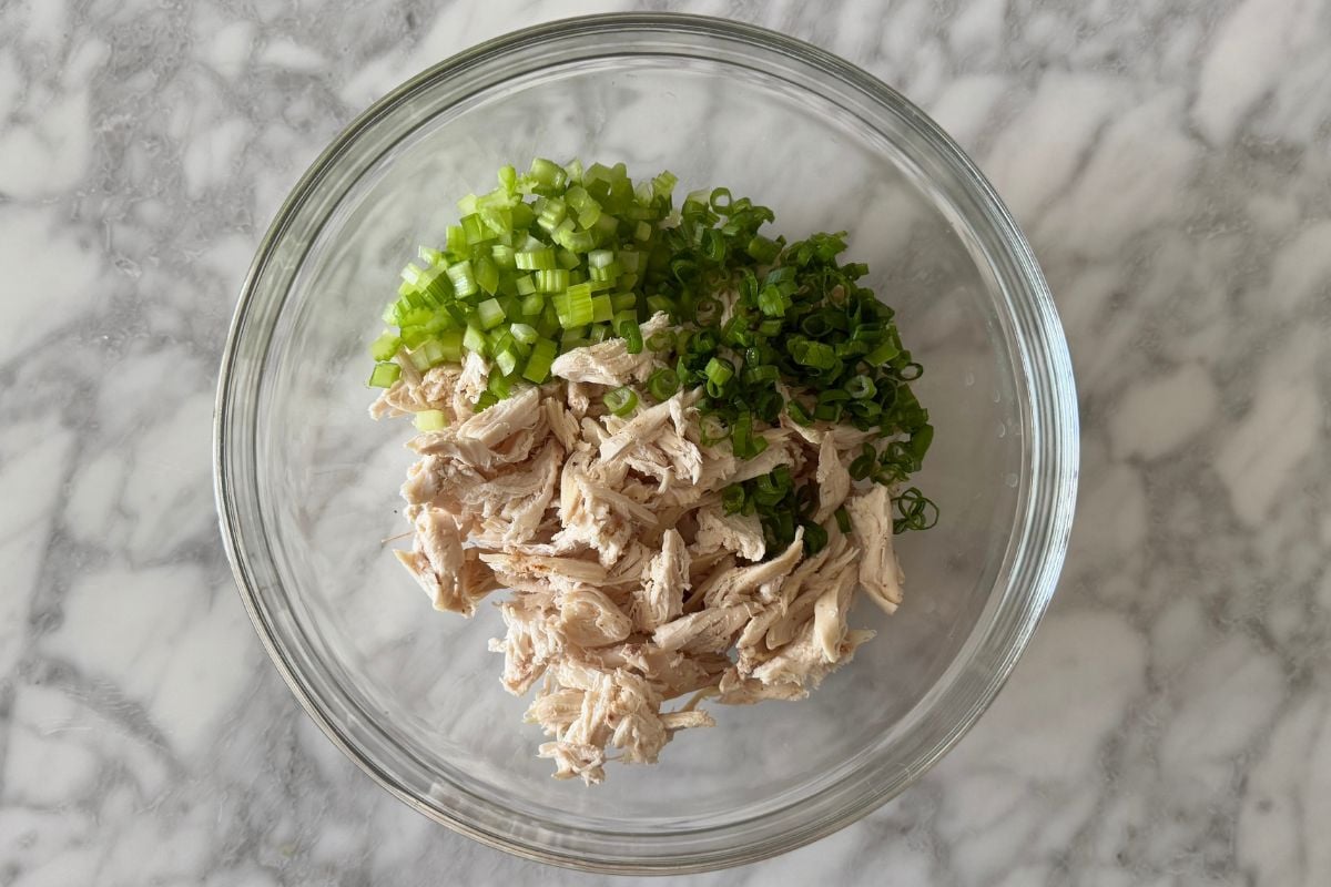 Cooked chicken in bowl with celery and green onions