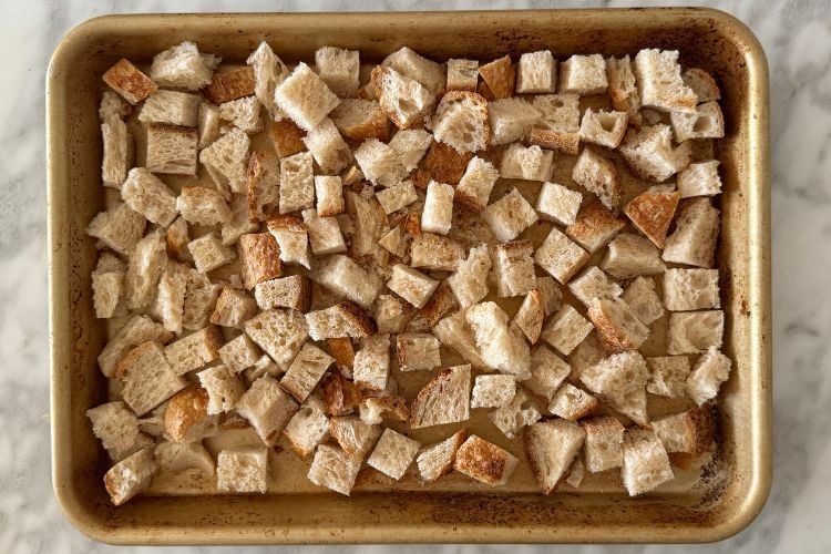 Dried cubed bread on sheet pan