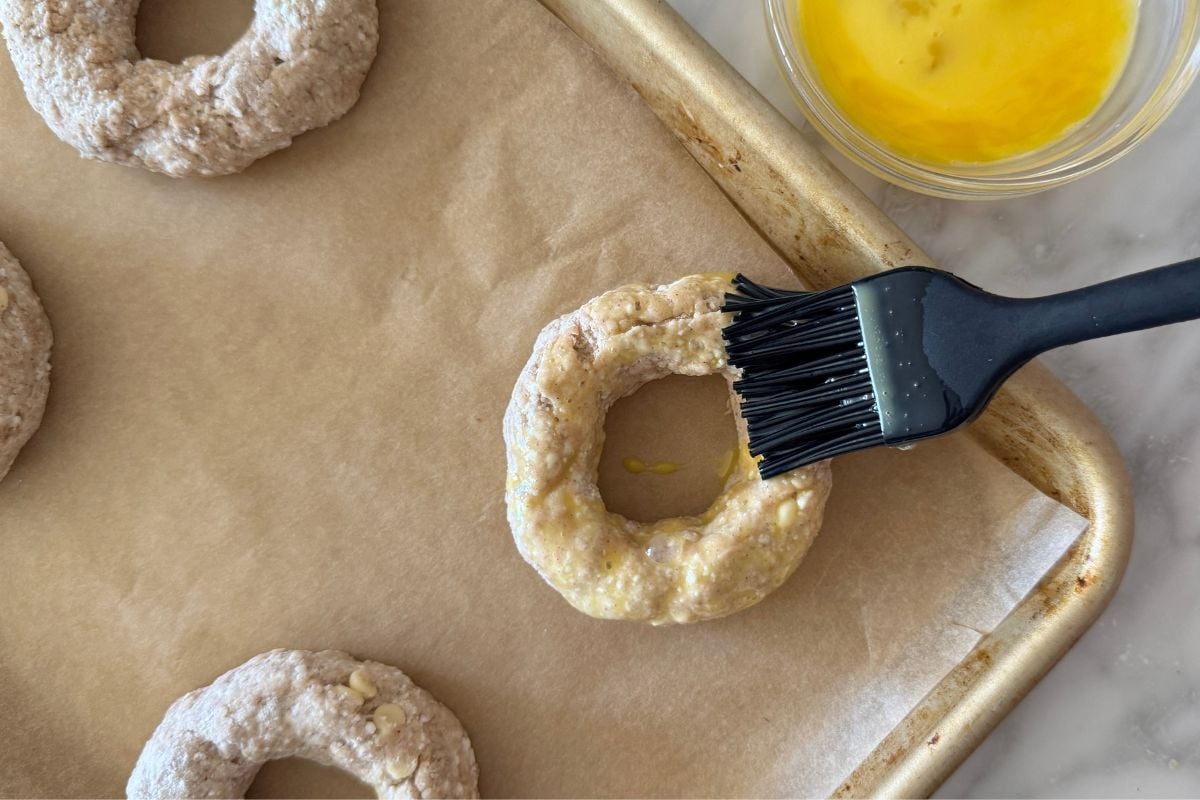 Egg wash on cinnamon crunch bagels on sheet pan
