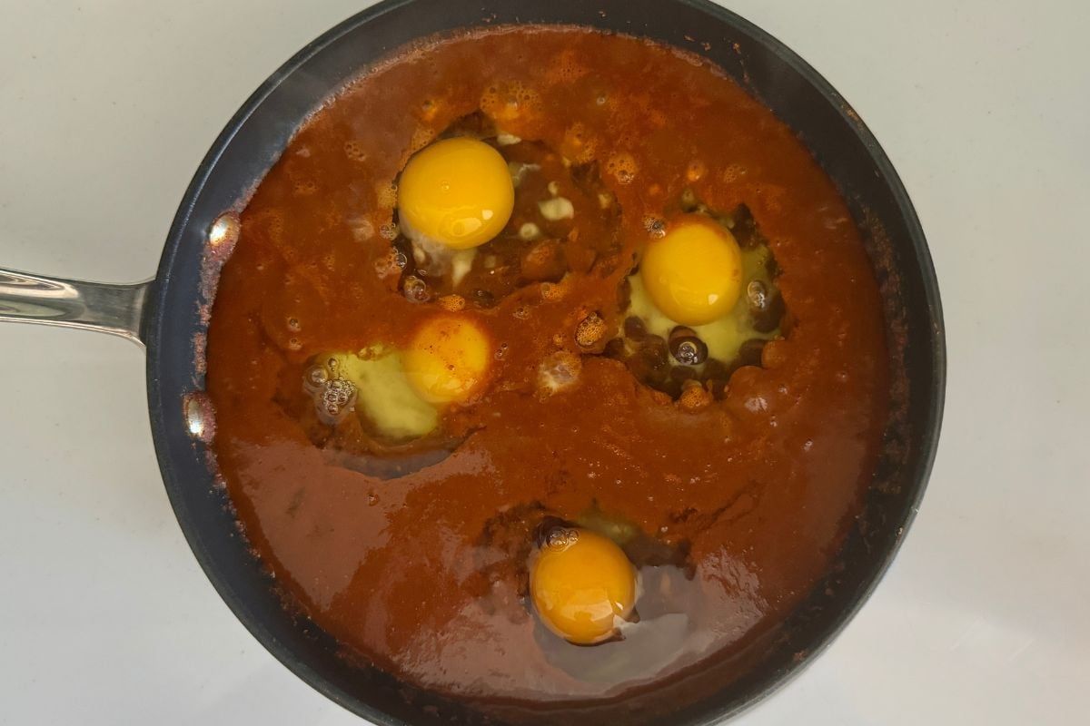 Eggs in skillet with enchilada sauce