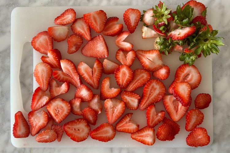 Hulled and sliced strawberries on cutting board