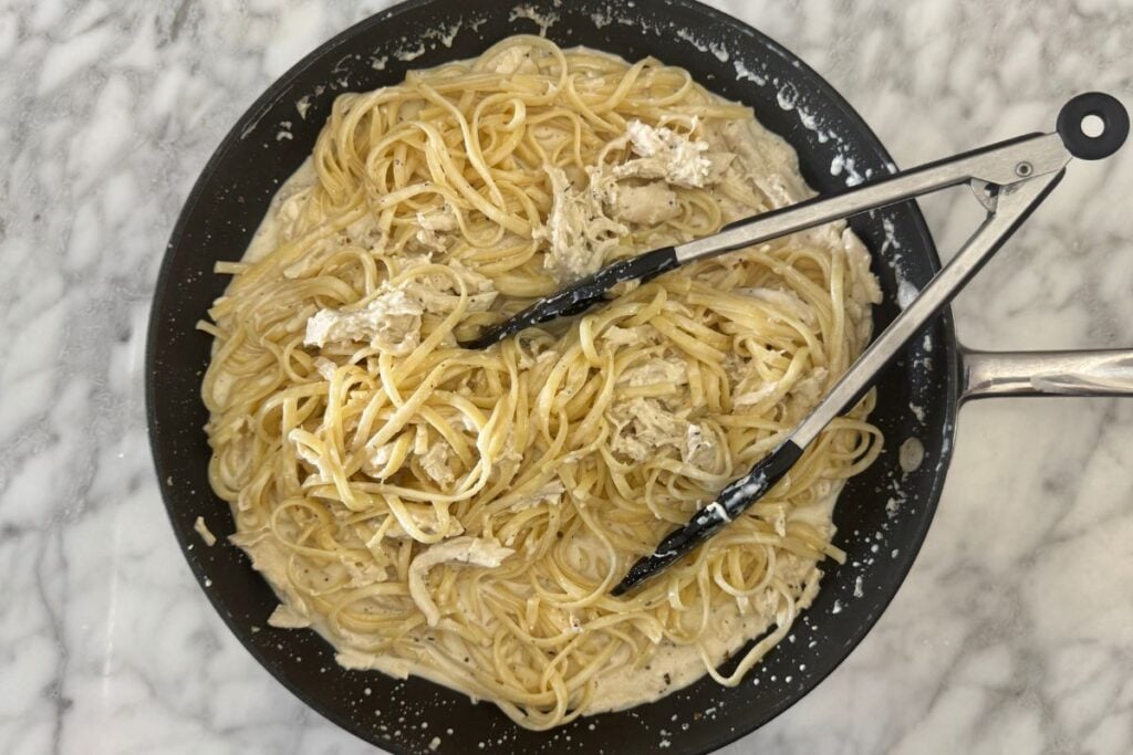 Mixed chicken Alfredo linguine in a pan