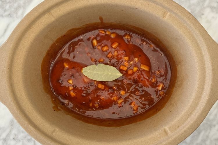 Mixed chicken tinga ingredients in a slow cooker