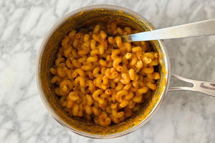 Pasta mixed in pumpkin mac and cheese sauce