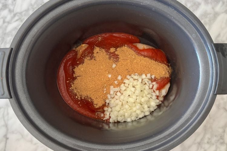 Taco seasoning and tomato sauce in slow cooker with chicken