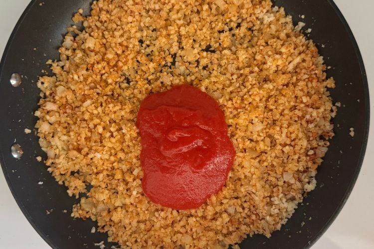 Tomato sauce in skillet for cauliflower Spanish rice