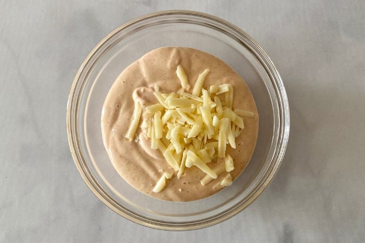 queso dip in a bowl with shredded cheese